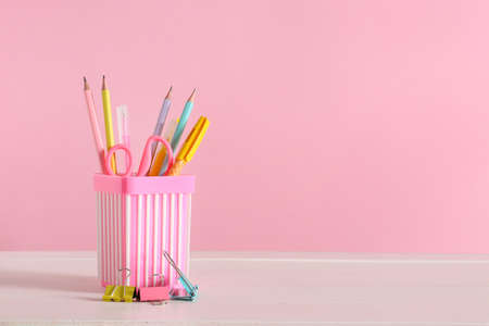 Holder with stationery on table against color backgroundの写真素材