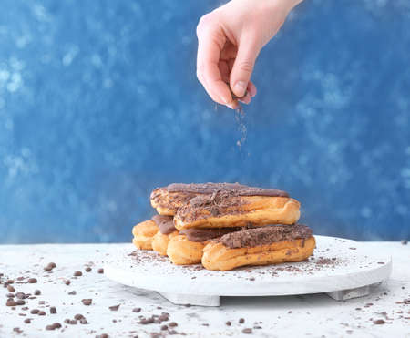 Female confectioner decorating tasty eclairs on tableの写真素材