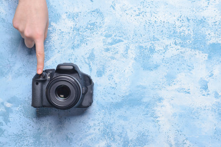 Female hand with modern photo camera on color background