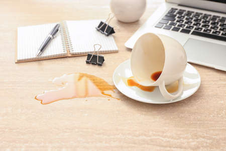 Overturned cup of coffee on office tableの写真素材