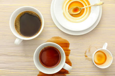 Cup, saucers and spilled coffee on wooden backgroundの写真素材