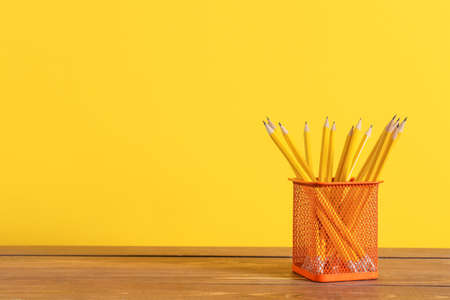 Holder with pencils on table against color backgroundの写真素材