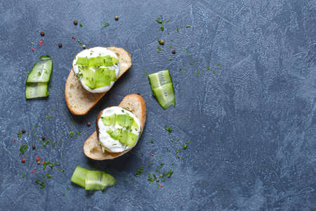 Tasty baked potato with sour cream, cucumber and bread on dark backgroundの写真素材