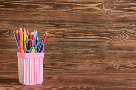 Holder with stationery on wooden backgroundの写真素材