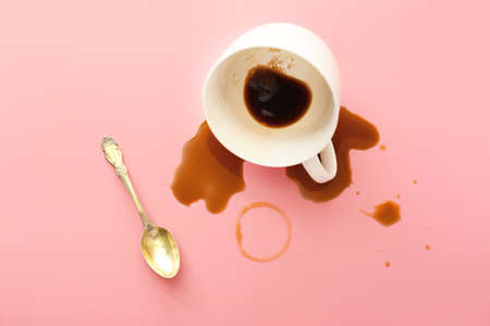 Overturned cup of coffee on color backgroundの写真素材