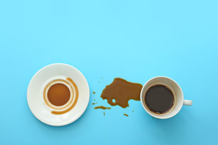 Cup, saucer and spilled coffee on color backgroundの写真素材