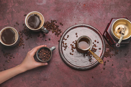 Female hand, cups of different coffee, jezve and grinder on color backgroundの写真素材