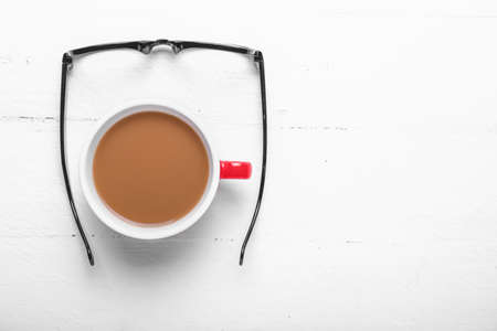 Cup of coffee with eyeglasses on white wooden backgroundの写真素材
