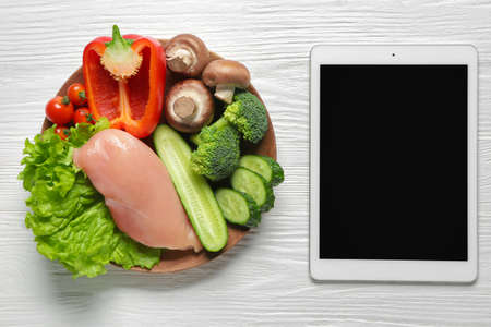 Tablet computer with healthy products on white wooden backgroundの写真素材