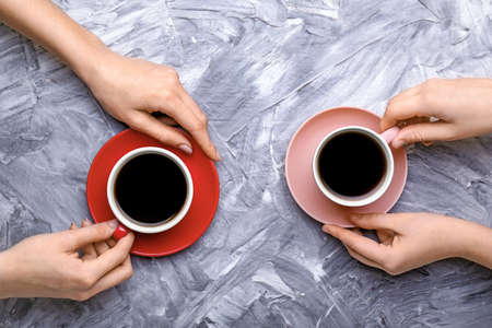 Female hands with cups of coffee on grunge backgroundの写真素材