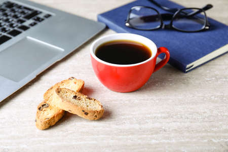Cup of coffee with cookies on table in officeの写真素材