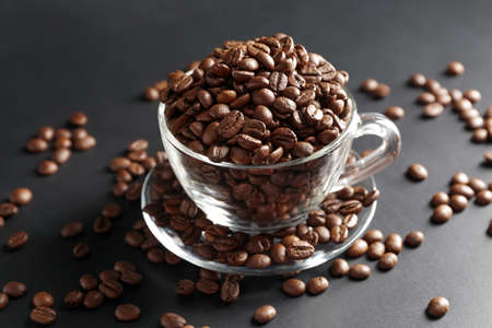 Cup with coffee beans on dark background