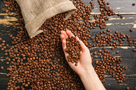 Woman taking coffee beans from tableの写真素材