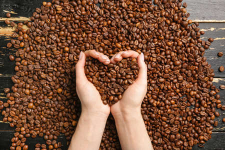 Female hands with coffee beans over tableの写真素材