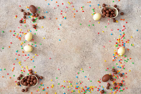 Frame made of chocolate eggs and candies on gray table