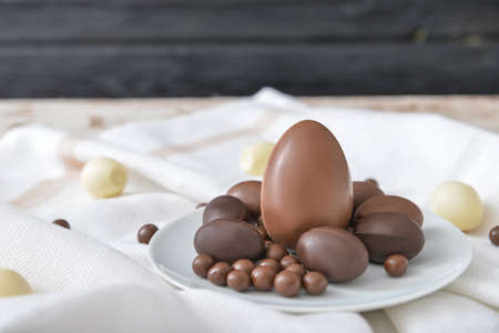 Plate with chocolate eggs and candies on tableの写真素材
