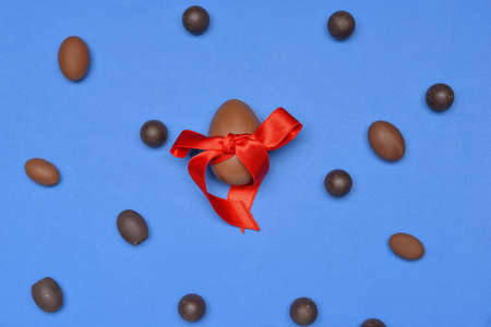 Chocolate eggs and candies on color background