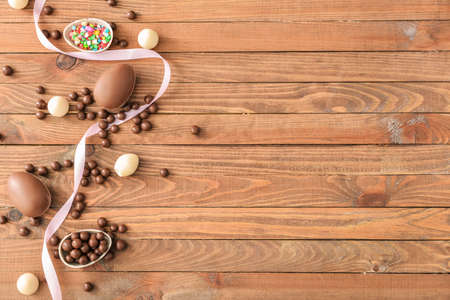 Chocolate eggs and candies on wooden tableの写真素材