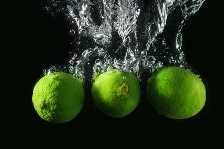 Falling of limes into water against dark background