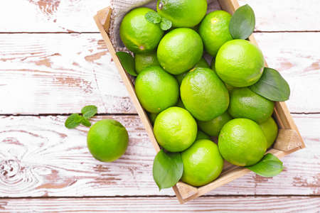 Box with fresh limes on wooden backgroundの写真素材