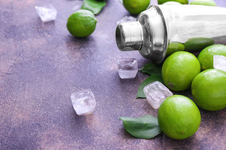 Fresh limes, shaker and ice cubes on gray backgroundの写真素材
