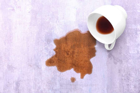 Overturned cup and spilled coffee on tableの写真素材