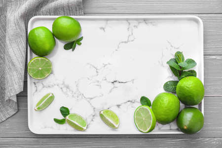 Plate with fresh limes on wooden backgroundの写真素材