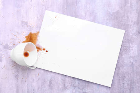Blank paper, overturned cup and spilled coffee on tableの写真素材