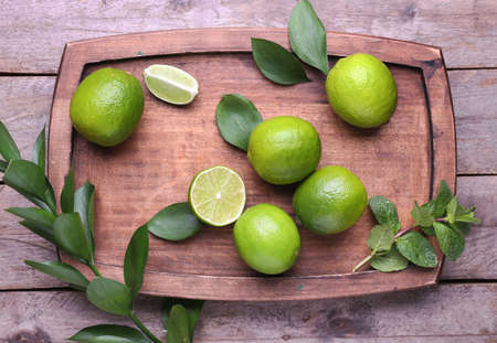 Fresh limes and board on wooden backgroundの写真素材