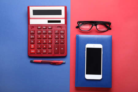 Calculator with stationery, mobile phone and eyeglasses on color backgroundの写真素材