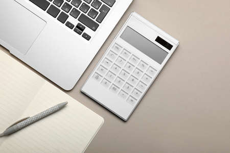 Calculator with stationery and laptop on gray backgroundの写真素材