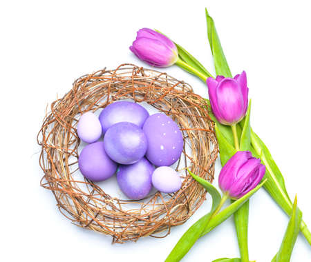 Nest with beautiful Easter eggs and flowers on white backgroundの写真素材