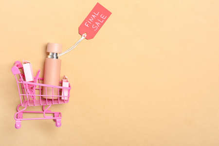 Bottle of perfume for sale with shopping cart on color backgroundの写真素材