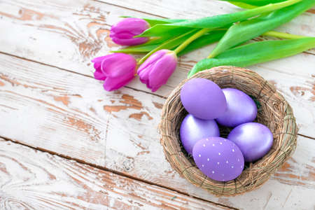 Nest with beautiful Easter eggs and flowers on tableの写真素材