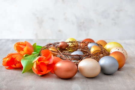 Nest with beautiful Easter eggs and flowers on gray backgroundの写真素材