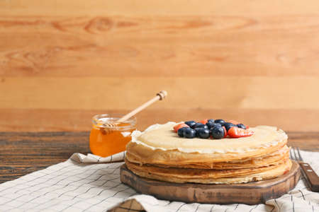 Tasty blini with berries and honey on tableの写真素材