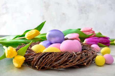 Nest with beautiful Easter eggs and flowers on gray backgroundの写真素材
