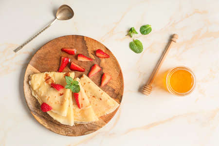 Tasty blini with berries and honey on tableの写真素材