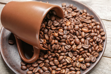 Cup and plate with coffee beans on tableの写真素材