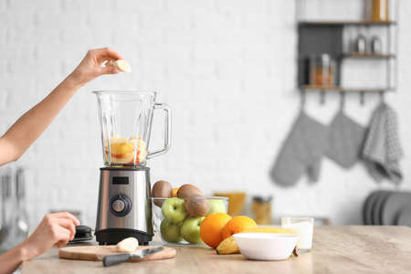 Young woman making fruit smoothie in kitchen at homeの写真素材