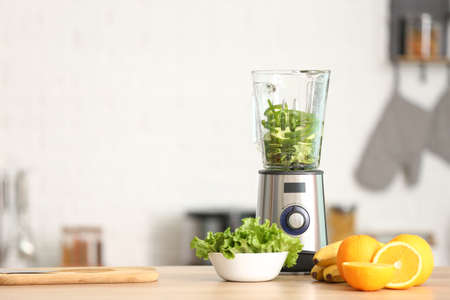 Modern blender with fresh fruits and vegetables on table in kitchenの写真素材