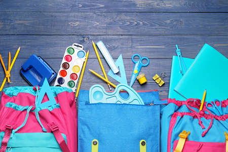 School backpacks and stationery on wooden backgroundの写真素材