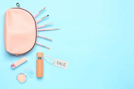 Bottle of perfume with makeup cosmetics and bag on color background
