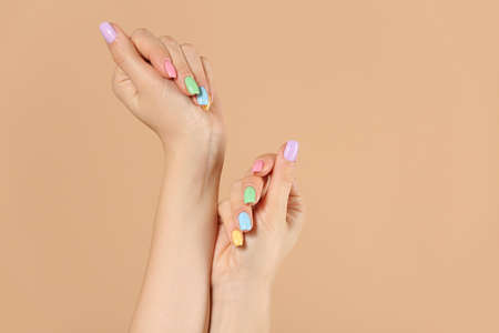 Hands of young woman with beautiful manicure on color backgroundの写真素材