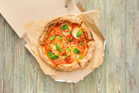 Cardboard box with delicious pizza Margherita on wooden backgroundの写真素材