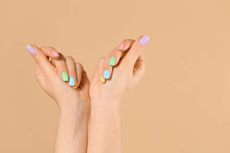 Hands of young woman with beautiful manicure on color backgroundの写真素材