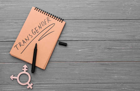 Word TRANSGENDER written in notebook and symbol on wooden backgroundの写真素材