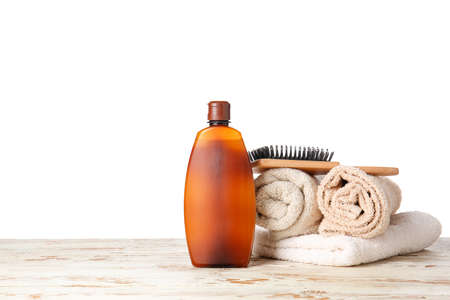 Shampoo, brush and towels on table against white backgroundの写真素材