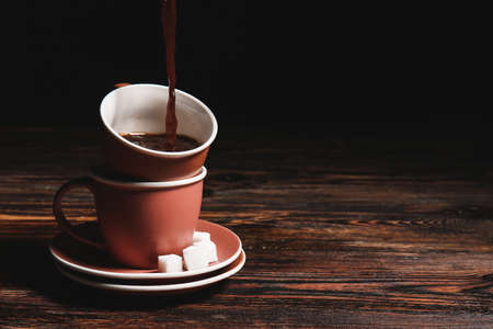 Pouring of hot coffee in cup on wooden tableの写真素材