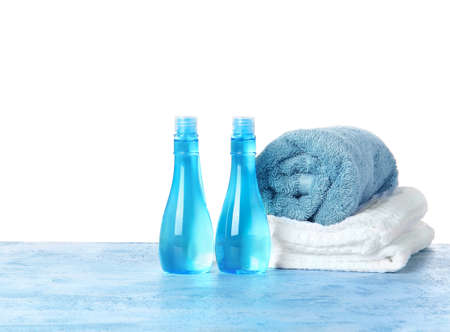 Shampoo and towels on table against white backgroundの写真素材